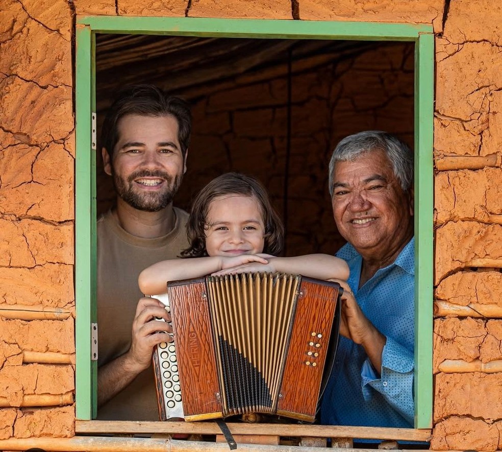 Luizinho Calixto com o neto e o filho, Thiago Calixto. O legado do pai segue firme no livro “Puxando o fole: a sanfona de 8 baixos e a alma do Nordeste”, de autoria dele. Obra que deve ser lançada ainda este ano. Três gerações ligadas pelo som do fole, respeito e memória — Foto: Roxanny Fotografia /  Reprodução Instagram