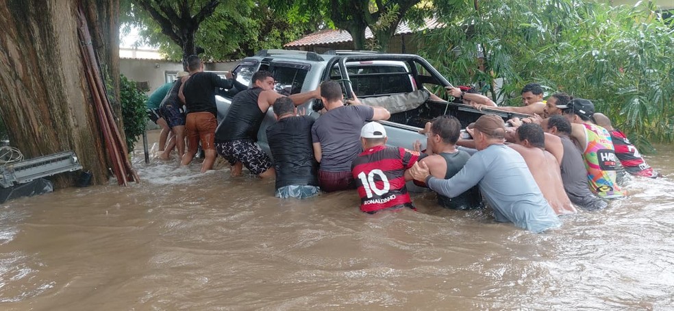 Homens ajudam a empurrar caminhonete que ficou boiando durante alagamento — Foto: Reprodução