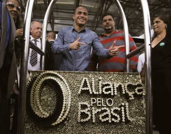Apoiadores posam com obra feita de cartuchos de balas com nome e símbolo do partido - Pedro Ladeira/Folhapress