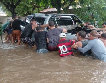Homens ajudam a empurrar caminhonete que ficou boiando durante alagamento — Foto: Reprodução